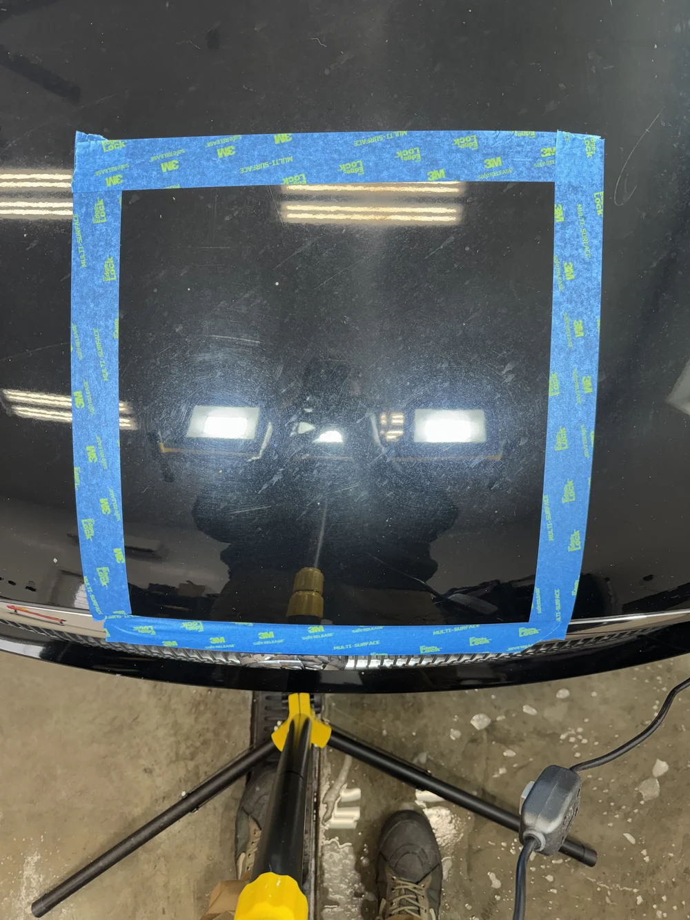 Vehicle paint before correction showing swirl marks in a taped test section